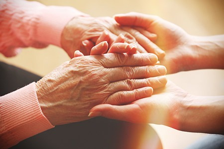Older woman and younger woman holding hands.