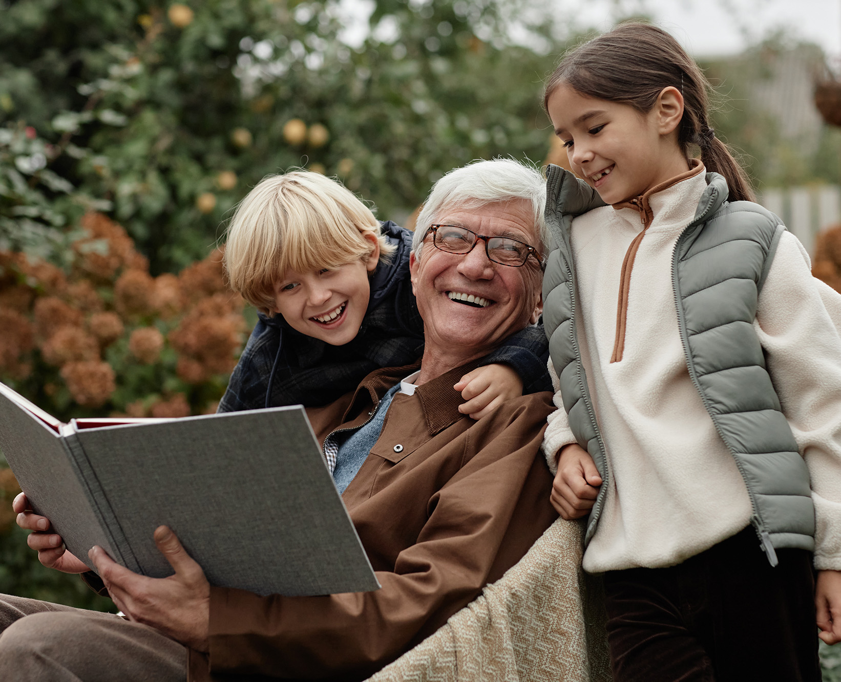 Senior Man Laughing with Grandchildren While Reading Storybook