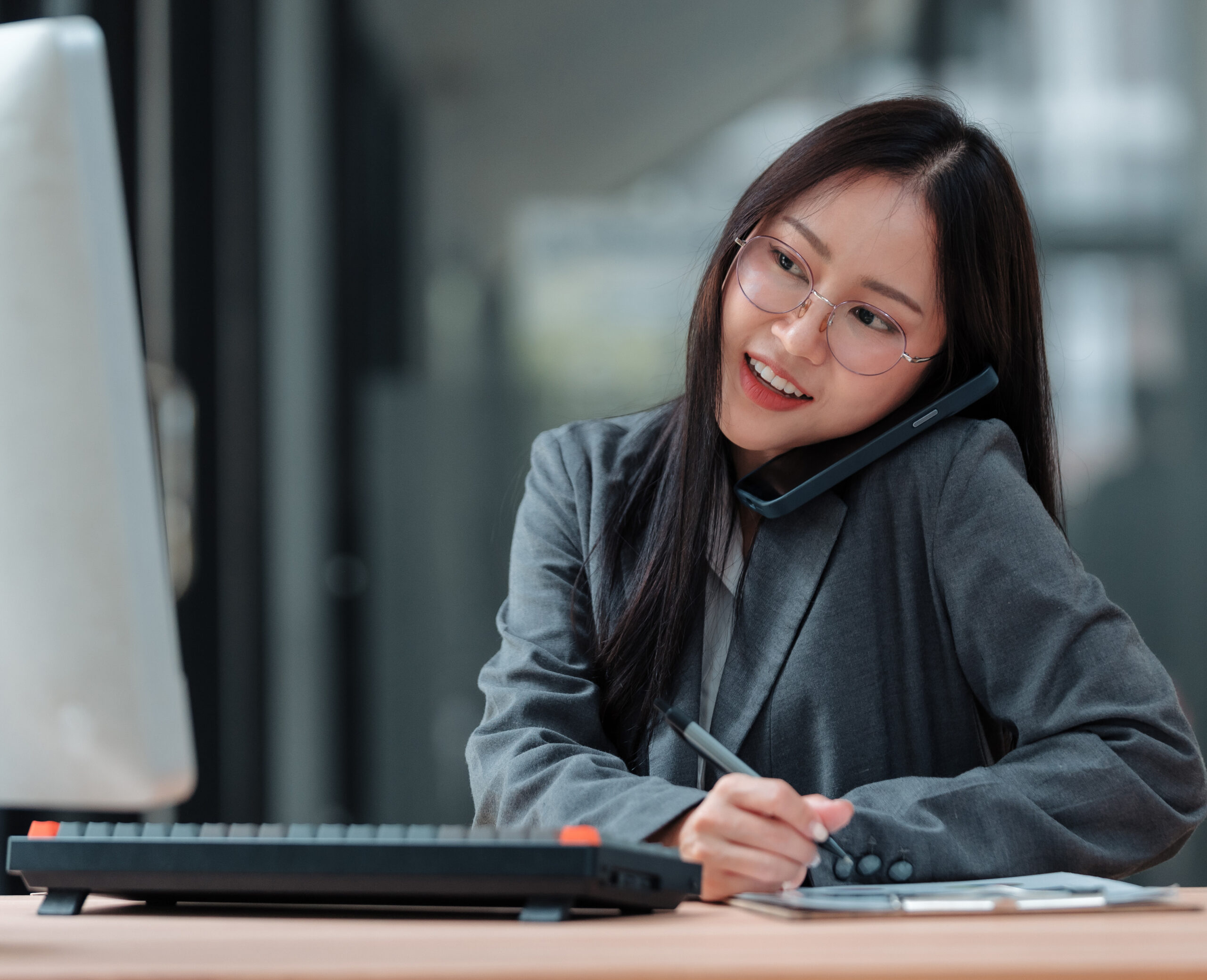 Woman talking on phone and taking notes in office