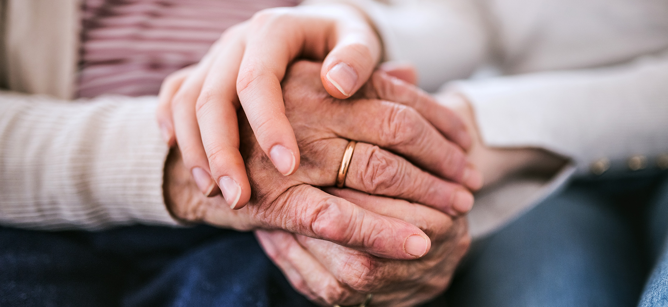 Hands of young woman and older woman at home.